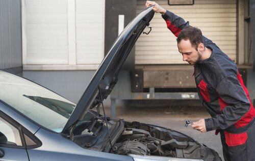 Un mecánico revisando la parte delantera de un coche